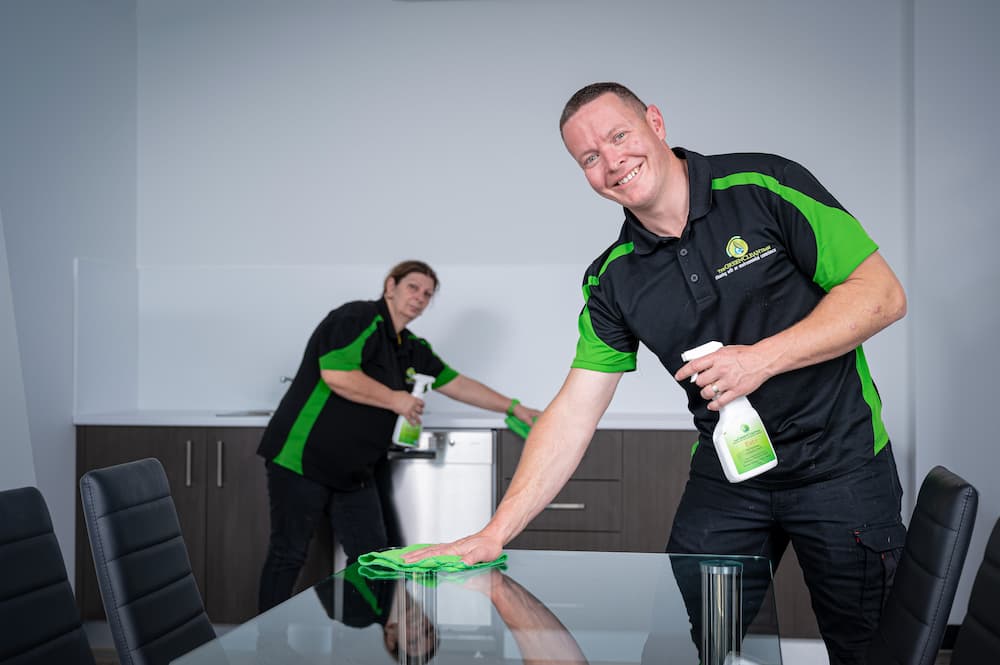 Two Green Clean Team staff members completing an eco-friendly commercial cleaning service in Bendigo, Central Victoria. The staff member in the foreground is wiping a table.