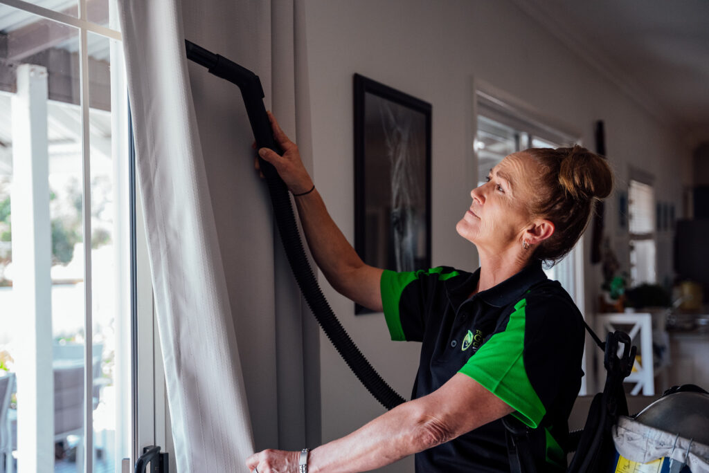 Green Clean Team staff member vacuuming curtains during an eco-friendly home cleaning service in Bendigo.