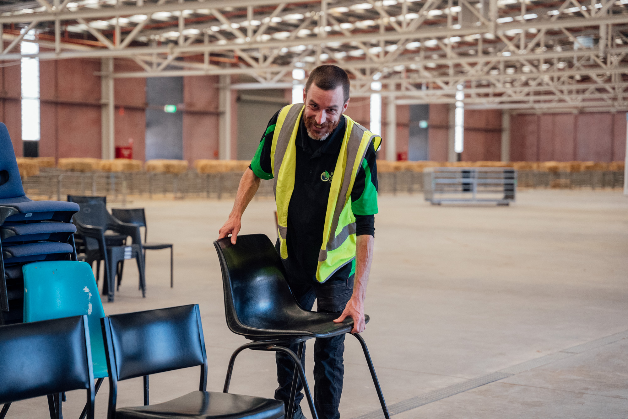 Green Clean Team staff member stacking chairs in stadium as part of post-event cleaning service in Central Victoria